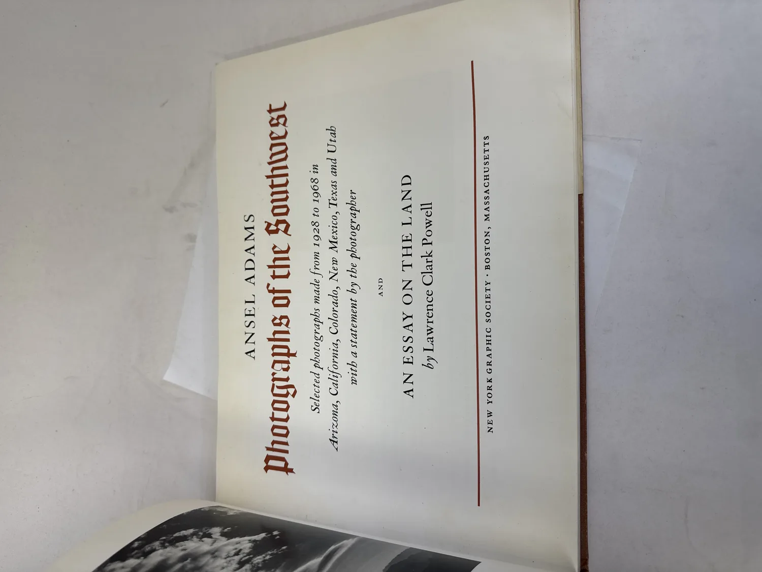 Title page of Photographs of the Southwest by Ansel Adams showing blackletter title, subtitle listing selected photographs made from 1928 to 1968 in Arizona California Colorado New Mexico Texas and Utah with a statement by the photographer, and An Essay on the Land by Lawrence Clark Powell, New York Graphic Society Boston Massachusetts. Photographed at the New Mexico Literacy Project sorting desk in Albuquerque.