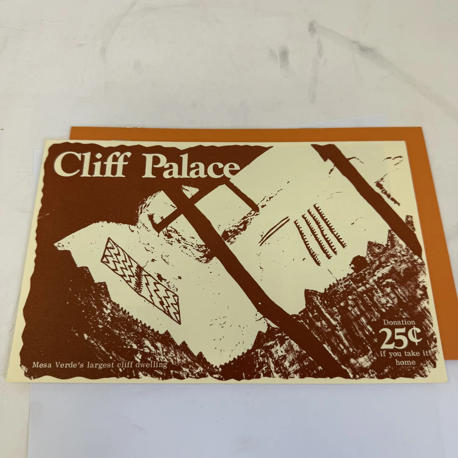 Vintage Cliff Palace interpretive brochure from Mesa Verde National Park — cream and brown card with stylized illustration of Mesa Verde's largest cliff dwelling, Donation 25 cents if you take it home. Shown alongside the orange Spruce Tree House brochure. Southwest National Park Service ephemera found in an Albuquerque estate donation to the New Mexico Literacy Project.