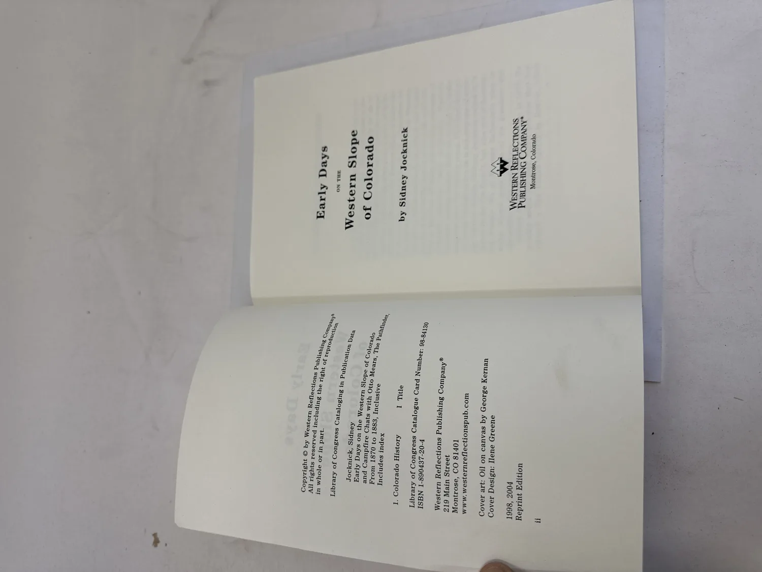 Title page and copyright page of Early Days on the Western Slope of Colorado by Sidney Jocknick. Western Reflections Publishing Company, Montrose, Colorado. ISBN 1-890437-20-4, LOC 98-84130. 1998 original, 2004 Reprint Edition. Cover art oil on canvas by George Kernan, cover design Ilene Greene. Photographed at the New Mexico Literacy Project sorting desk in Albuquerque.