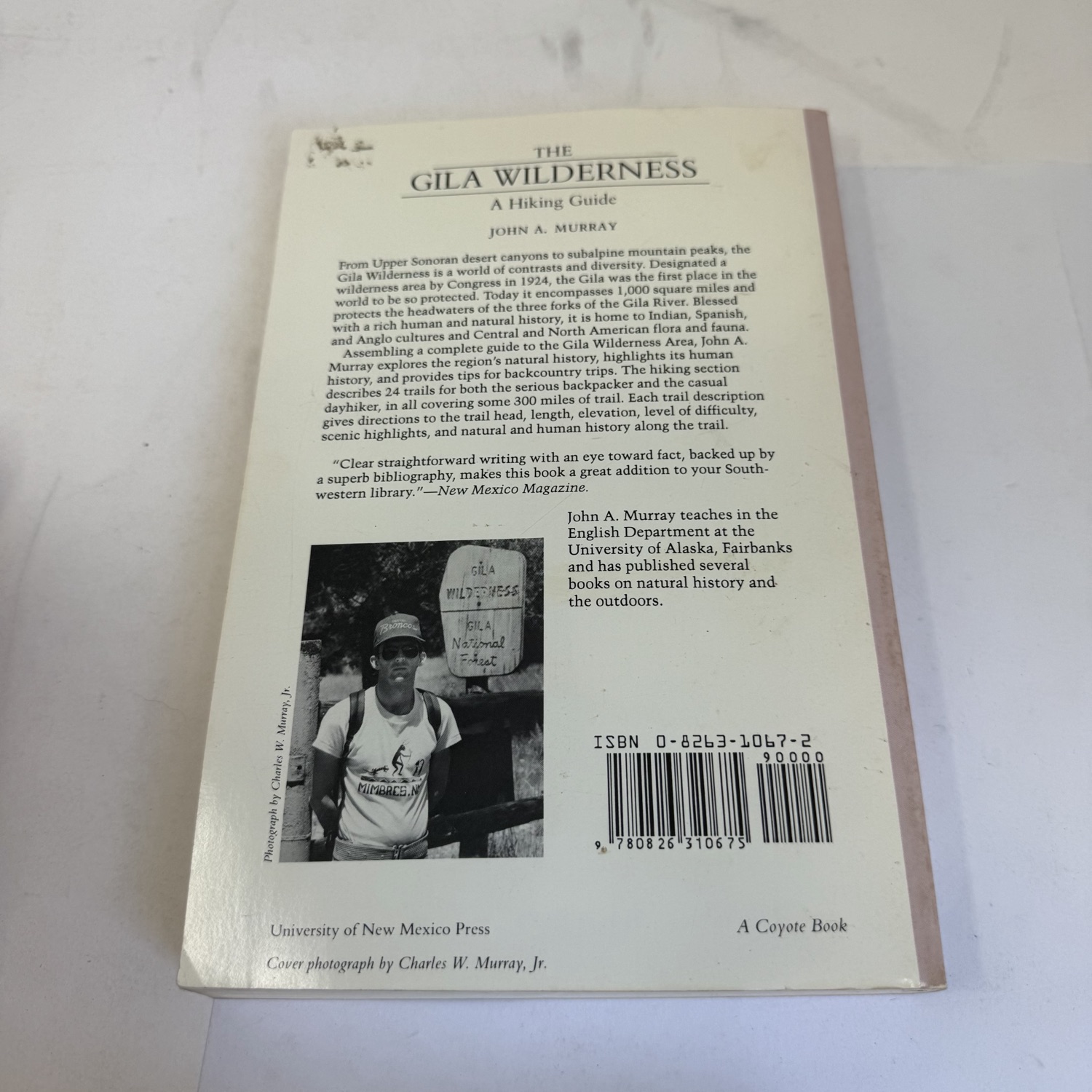 Back cover of The Gila Wilderness A Hiking Guide by John A. Murray — full book description, NM Magazine blurb praising clear straightforward writing, author photo at Gila Wilderness Gila National Forest sign wearing Mimbres t-shirt, ISBN barcode, A Coyote Book UNM Press.