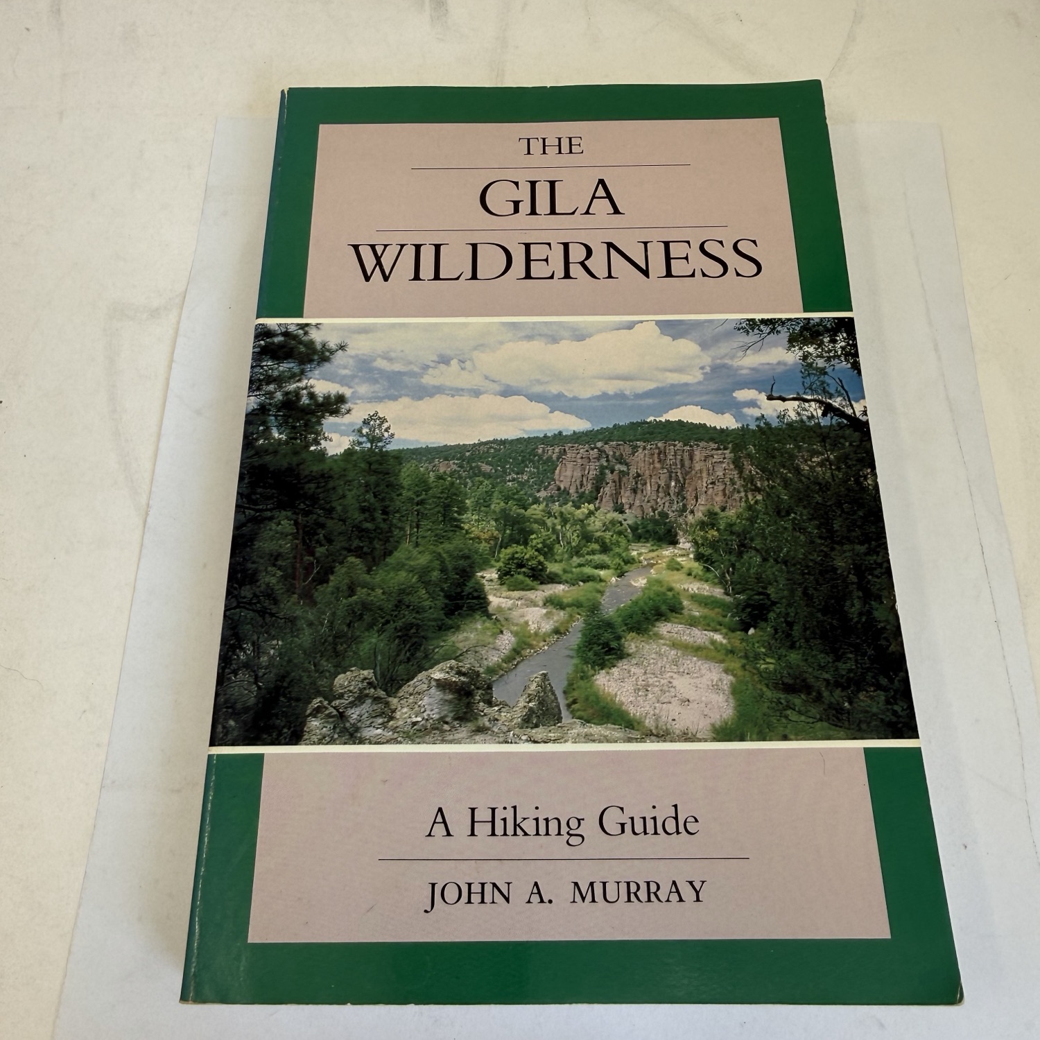 Front cover of The Gila Wilderness A Hiking Guide by John A. Murray — UNM Press Coyote Book series, green borders with color landscape photograph of Gila canyon creek and cliff walls by Charles W. Murray Jr.