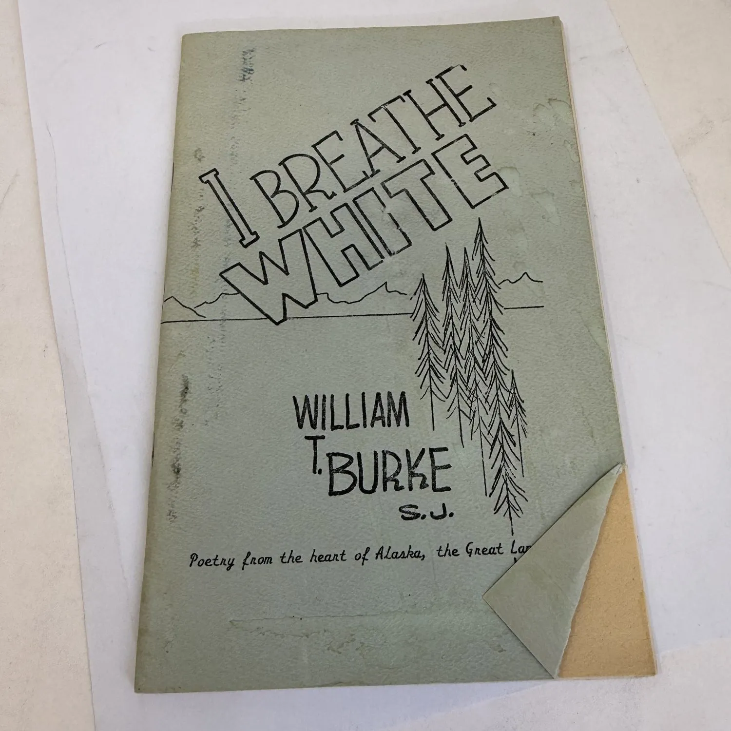 Front cover of I Breathe White Poetry from the Heart of Alaska the Great Land by William T. Burke S.J., Silver Wings Press 1987, pale green chapbook cover with hand-lettered title and pen-and-ink illustration of Alaskan spruce trees and mountain range. Jesuit missionary poetry from a parish extending over 400 highway miles of Alaska. Found in a New Mexico estate cleanout.