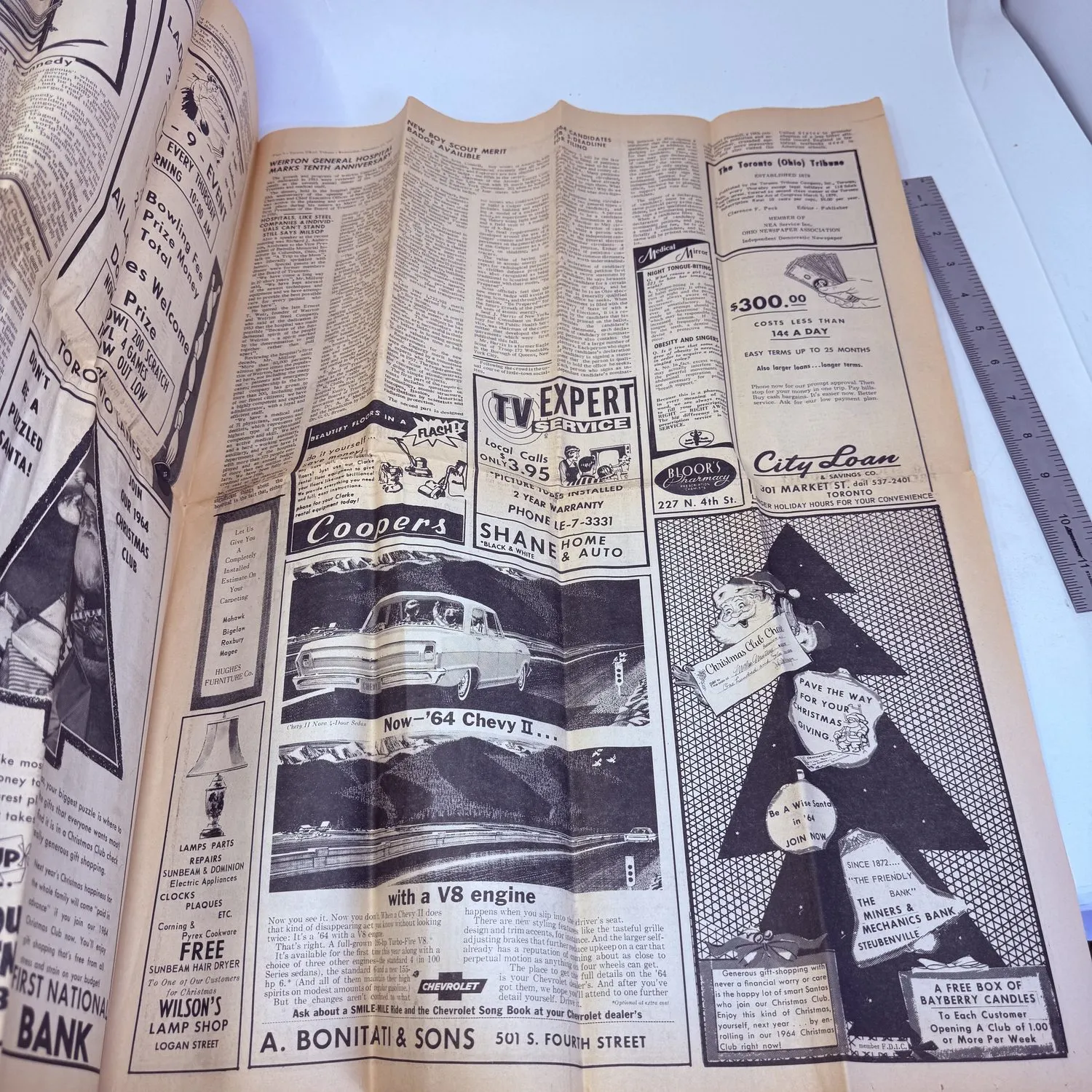Back page of the Toronto Tribune November 27 1963, filled with vintage 1963 advertisements including a 1964 Chevy II with V8 engine, Cooper's, Shane Home and Auto, TV Expert Service with $3.95 house calls, City Loan, A. Bonitati and Sons at 501 S. Fourth Street, Wilson's Lamp Shop, and the Miners and Mechanics Bank. Small-town American commerce frozen in time.