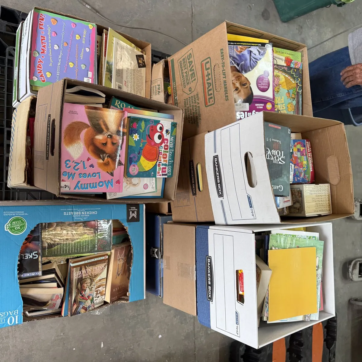 Full pallet of children's books in boxes stacked two and three high, being prepared for distribution to rural New Mexico communities through a volunteer at La Vida Llena retirement community, Albuquerque, June 2026
