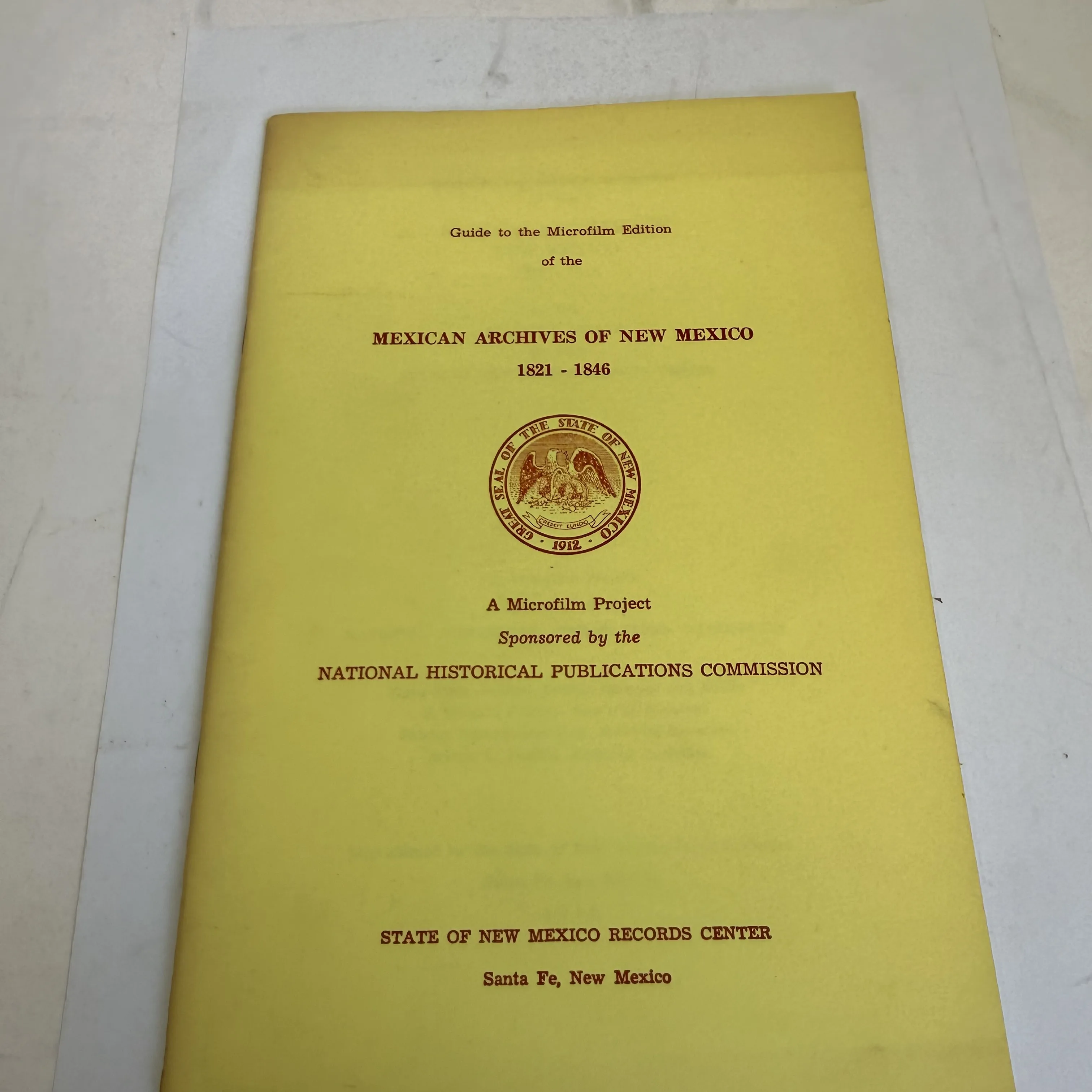 Front cover of Guide to the Microfilm Edition of the Mexican Archives of New Mexico 1821-1846, published by the State of New Mexico Records Center Santa Fe 1969. Yellow cover with the Great Seal of the State of New Mexico dated 1912. Government institutional publication found in a New Mexico estate cleanout by the New Mexico Literacy Project.