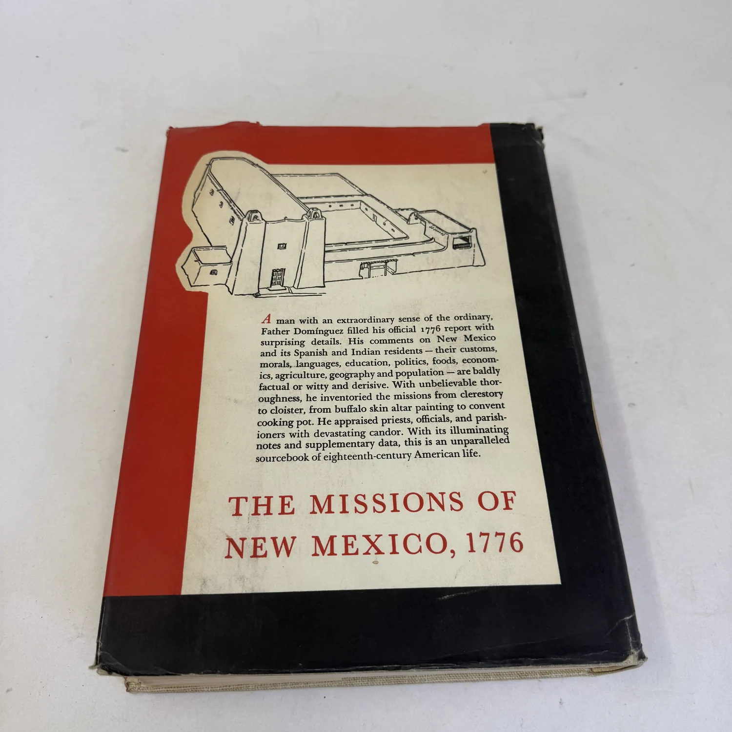 Back panel of the dust jacket of The Missions of New Mexico, 1776 with a drawing of a mission church and the publisher description of the Dominguez report, photographed at New Mexico Literacy Project