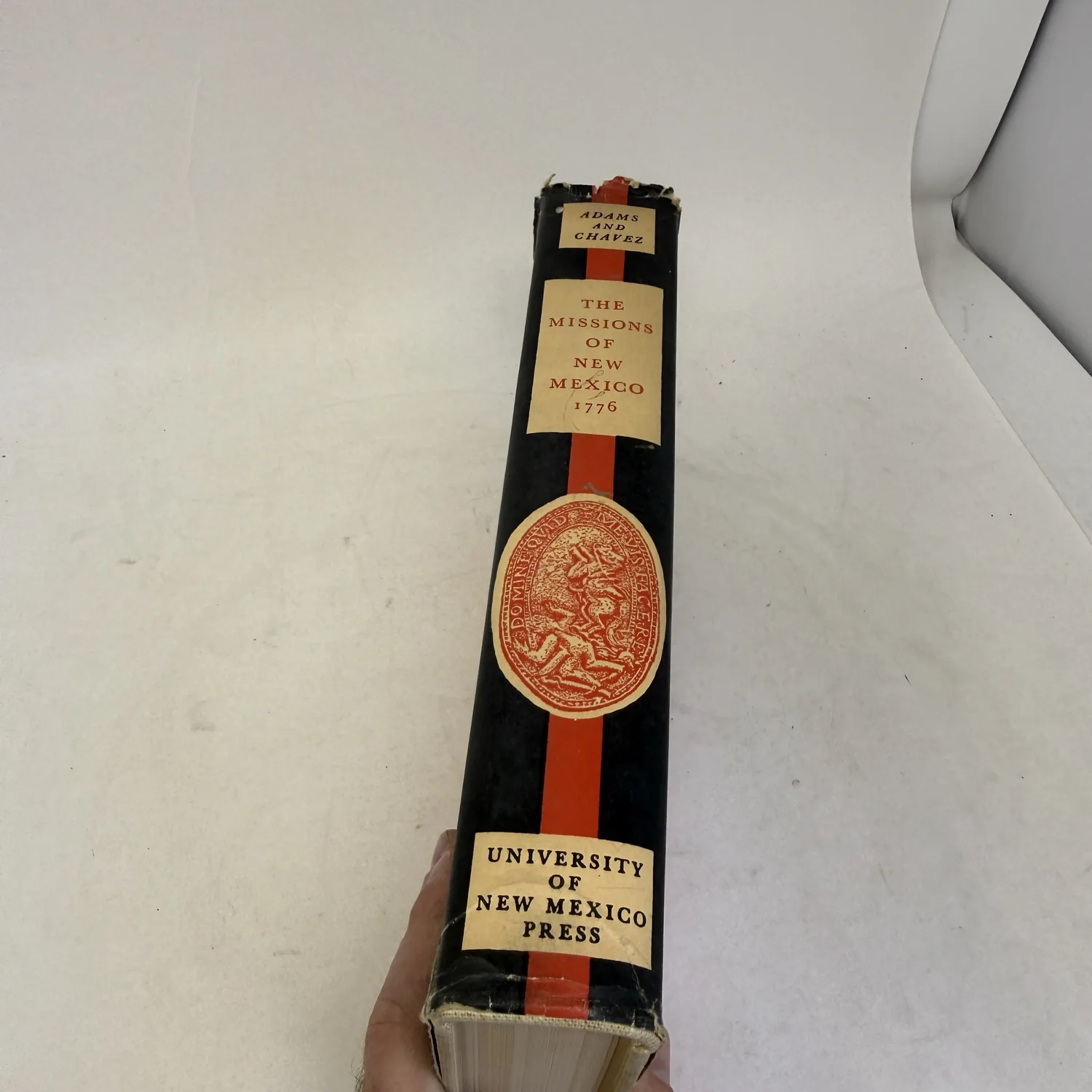 Dust jacket spine of The Missions of New Mexico, 1776 reading Adams and Chavez, with the University of New Mexico Press imprint at the foot, photographed at New Mexico Literacy Project