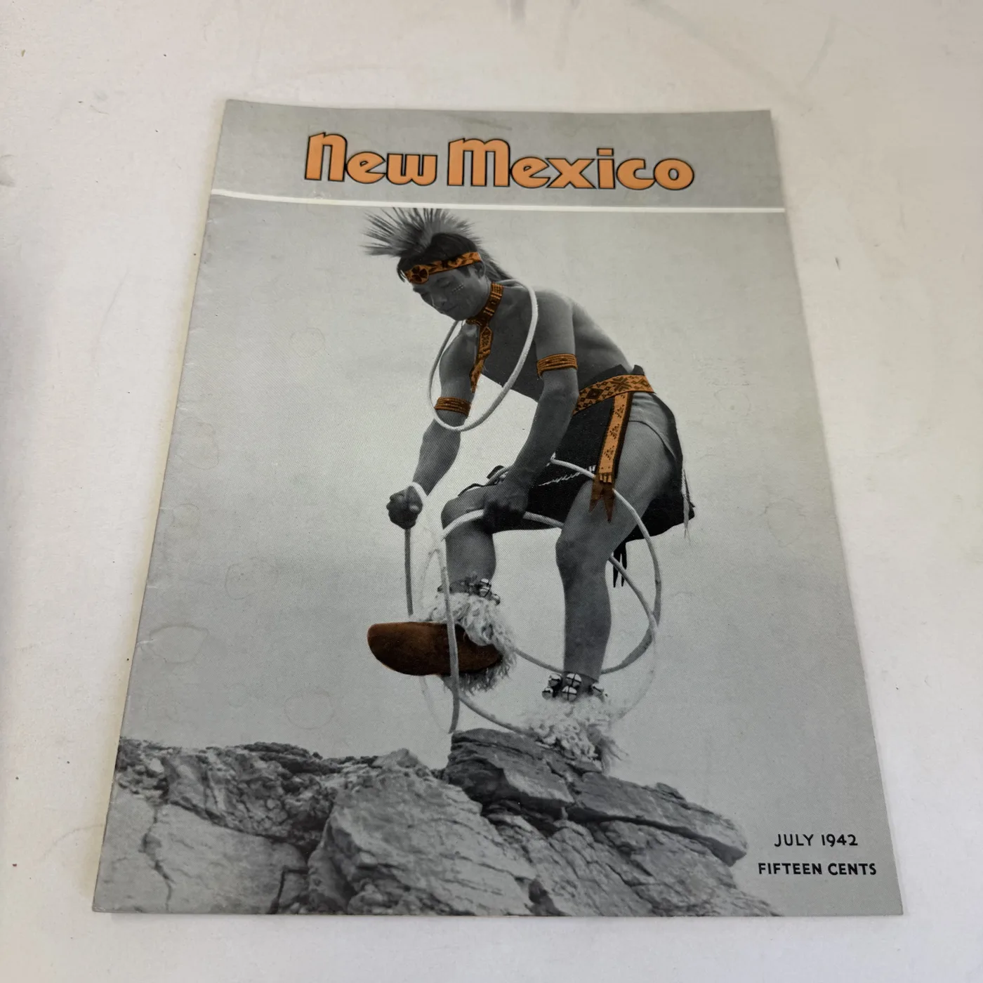 New Mexico Magazine July 1942 cover: hoop dancer balanced mid-step on bare rock, fifteen cents — photographed at New Mexico Literacy Project